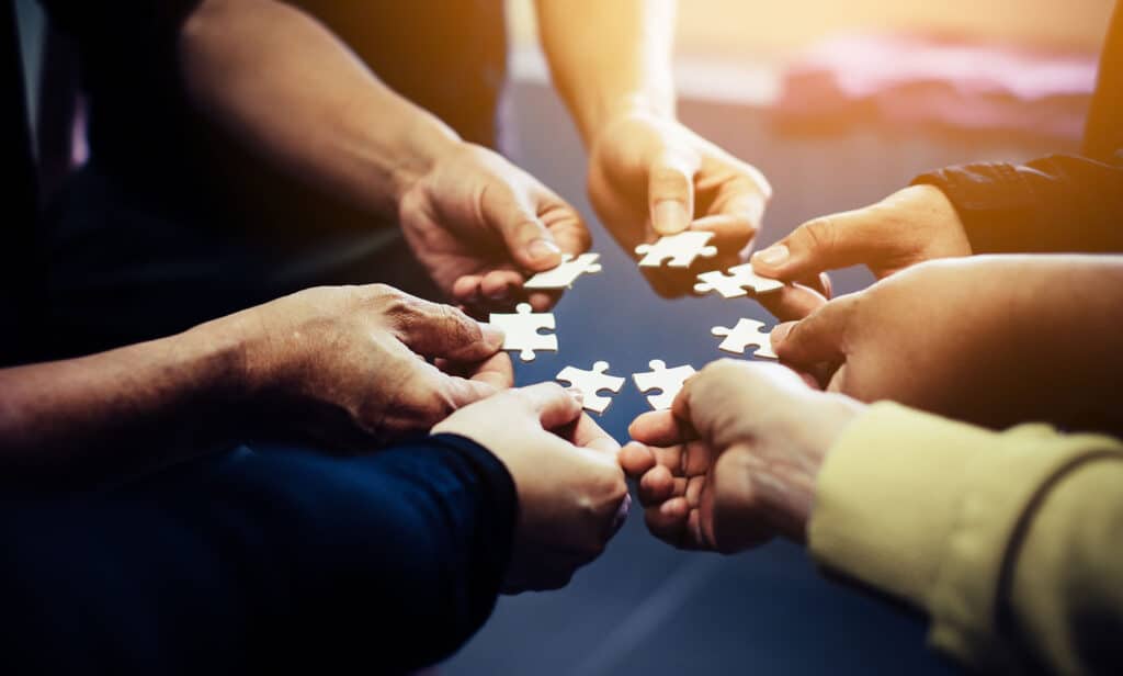 Close-up photo of businesspeople holding jigsaw puzzle